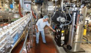 A worker inspects machinery in a factory setting.